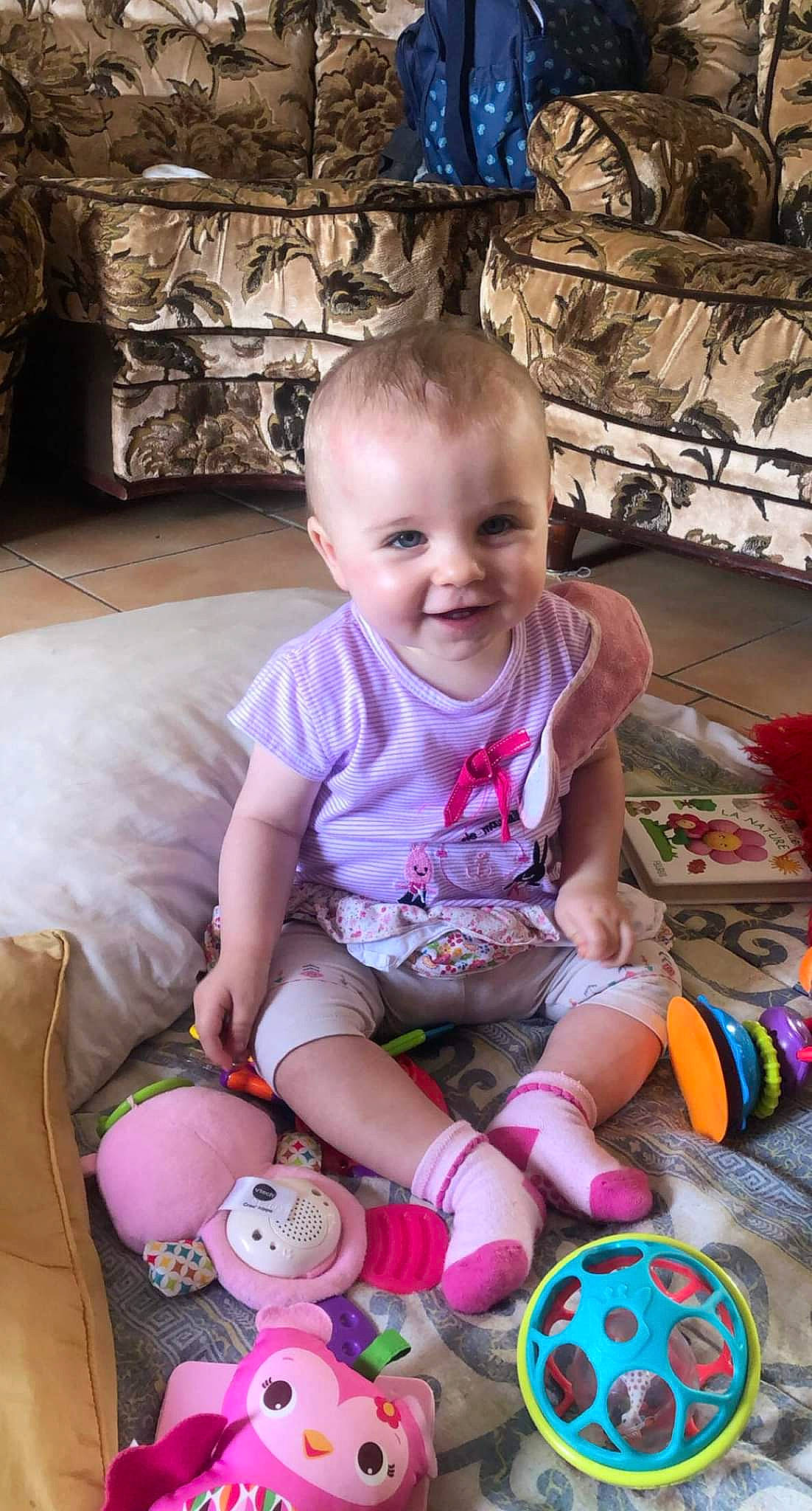 Évangéline a rejoint le concours — aidez-le/la à gagner de superbes lots ! baby, baby_toddler_clothing, blue, cheek, child, comfort, fun, happy, joy, people, person, pink, play, purple, shorts, sitting, skin, smile, sock, t_shirt