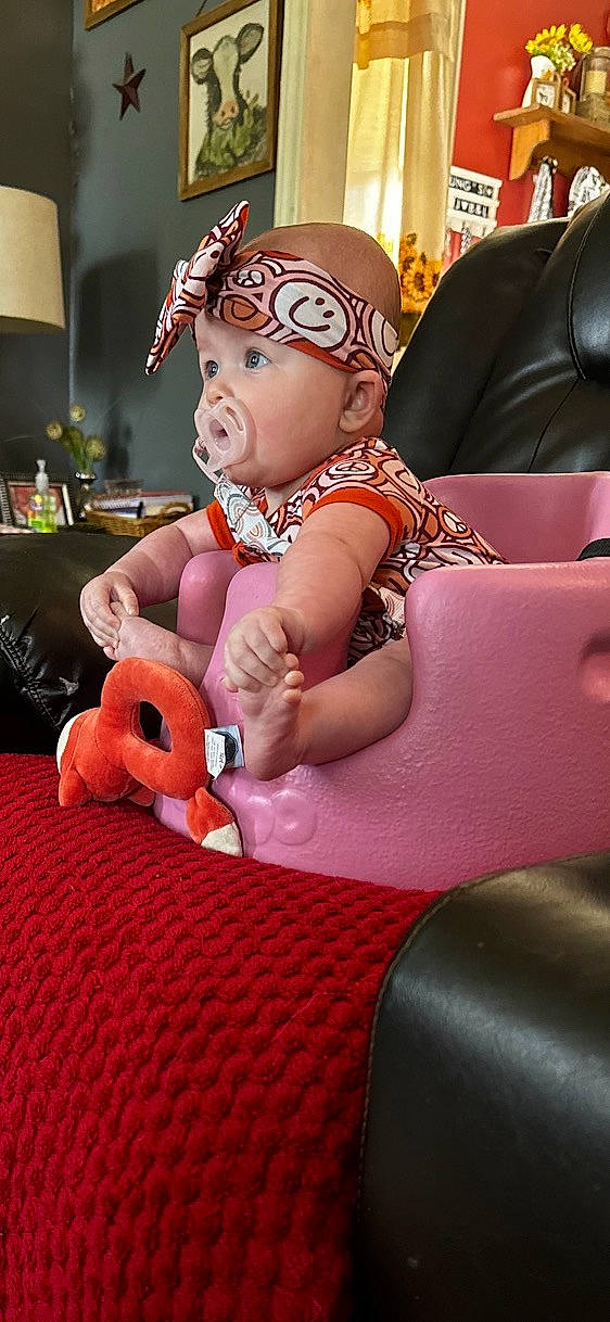 Emberleigh is registered to the contest to win money with this photo: baby, baby_products, baby_toddler_clothing, cap, carmine, child, comfort, costume_hat, event, fashion_accessory, fun, headwear, lap, magenta, person, pink, room, sitting, stuffed_toy, thumb