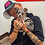 Coral Rae joined the competition — help win amazing prizes! person, dog, puppy, indoor, tattoo, bracelet, ring, cap, black_hoodie, jeans, floor, wall, cuddle, cute, pet, small_dog, merle, affection, love, casual