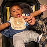 Messiah joined the competition — help win amazing prizes! baby, child, car_seat, bib, bear_design, hand, adult_hand, floor, wooden_floor, clothing, sleeves, pants, bracelet, smiling, happy, indoor, person, infant, cute, playful