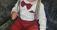 Messiah is registered to the contest to win money with this photo: toddler, child, boy, cap, bow_tie, suspenders, polka_dot_shirt, maroon_pants, barefoot, smile, face, portrait, sitting, couch, furniture, indoor, cute, fashion, happy, person