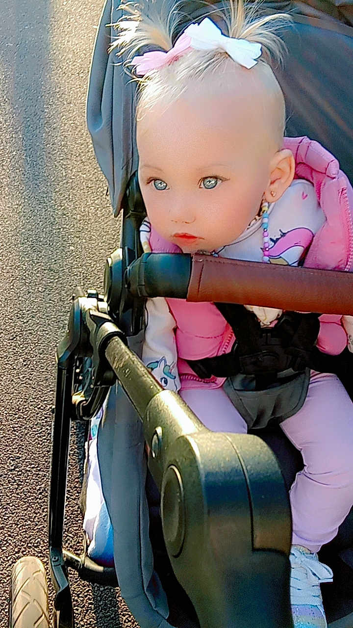 Shana participe au concours pour gagner de l'argent avec cette photo : baby, beads, child, clothing, cute, daylight, expression, face, outdoor, pavement, person, pigtails, pink_jacket, safety_harness, shoes, side_view, stroller, sunlight, toddler, unicorn