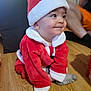 Francescu-Maria a rejoint le concours — aidez-le/la à gagner de superbes lots ! baby, child, christmas, costume, cute, festive, floor, funny_expression, happy, holiday, indoor, infant, person, red_clothing, santa_costume, santa_hat, smiling, sock, white_fur_trim, wooden_floor