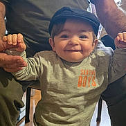 Francescu-Maria a rejoint le concours — aidez-le/la à gagner de superbes lots ! adult, cap, casual, child, clothing, face, floor, furniture, happy, holding_hands, indoor, legs, pants, person, playful, smile, support, sweatshirt, toddler, wooden_floor