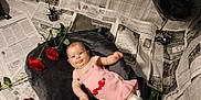 Odessa is registered to the contest to win money with this photo: baby, balloon, black_balloon, blanket, child, cute, face, flooring, gray_blanket, infant, lying_down, newspaper_background, pink_dress, portrait, props, red_roses, rose, smiling, studio_set, white_socks