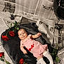 baby, balloon, black_balloon, blanket, child, cute, face, flooring, gray_blanket, infant, lying_down, newspaper_background, pink_dress, portrait, props, red_roses, rose, smiling, studio_set, white_socks
