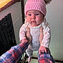 Odessa joined the competition — help win amazing prizes! baby, child, pink_hat, pom_poms, tattoo, hands, indoor, window, plaid_shirt, cute, infant, long_sleeve, patterned_clothing, person, skin, face, holding, cozy, warm_light, expression