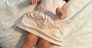Tania is registered to the contest to win money with this photo: toddler, child, smiling, happy, bed, blanket, dress, sandals, hair, person, indoors, cute, laying, skin, footwear, sleepwear, infant, young_child, cheerful, portrait