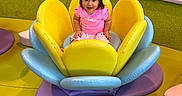 Tania joined the competition — help win amazing prizes! blue, child, colorful, cushions, flooring, flower_shaped_seat, green, hair_ponytail, happy, indoor, person, pink_clothing, play_area, playful, purple, seat, smiling, soft_play, toddler, yellow