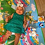 baby, child, green_dress, headband, play_mat, toy, stuffed_animal, colorful, floor, foot, infant, smiling, indoor, cute, happy, lying_down, alphabet, playtime, toddler, person