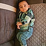 baby, child, plaid_shirt, denim_jeans, sneakers, couch, quilted_mat, indoor, portrait, casual_clothing, relaxed, curious, infant, home, fabric, seated, soft_lighting, comfortable, cute, young