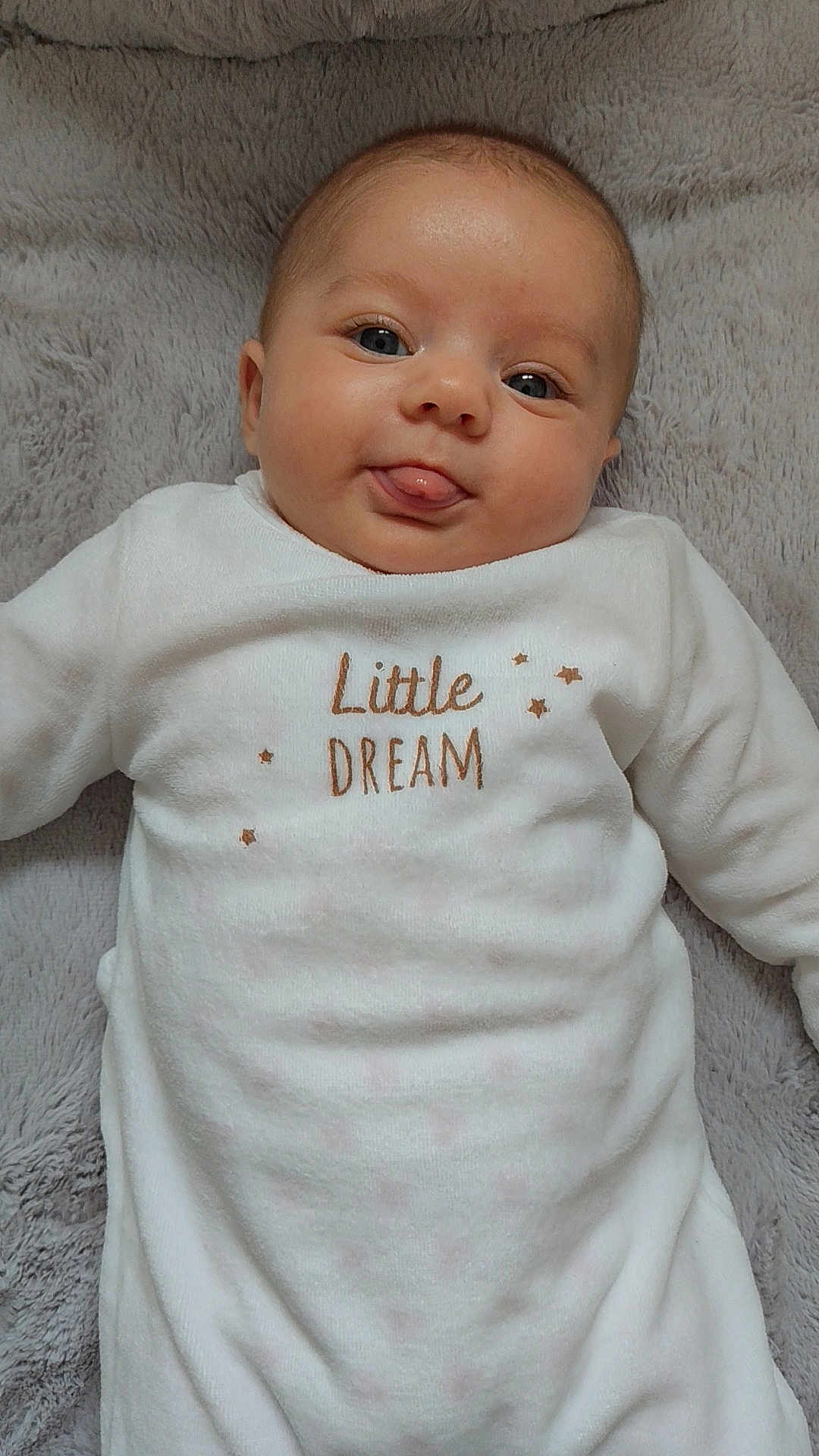 Luciana a rejoint le concours — aidez-le/la à gagner de superbes lots ! baby, infant, face, tongue, white_clothing, blanket, soft_texture, lying_down, cute, playful, smiling, child, portrait, indoors, cozy, close_up, skin, eyes, head, expression