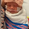 Aubrey is registered to the contest to win money with this photo: newborn, baby, infant, sleeping, hospital, medical_tape, nasal_tube, swaddled, blanket, bow, headband, portrait, close_up, face, eyes_closed, indoors, caregiver, bedding, striped_blanket, peaceful
