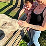 adult, animal, baby, bench, child, curious, family, farm, grass, holding, outdoor, parent, park, petting, pig, portrait, safely, smiling, sunlight, tattoo
