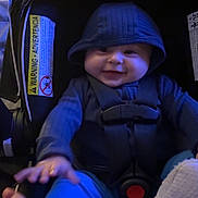 Jameson joined the competition — help win amazing prizes! baby, child, car_seat, hood, smile, infant, happy, clothing, seatbelt, foot, hand, blue_pants, dark_background, indoor, safety, cute, young_child, infant_toy, child_seat, apparel