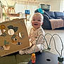 Léon a rejoint le concours — aidez-le/la à gagner de superbes lots ! baby, child, pajamas, toy_box, wooden_toy, bead_maze, indoor, living_room, couch, dog, floor, mat, smiling, playtime, furniture, animal_stickers, cute, happy, person, home