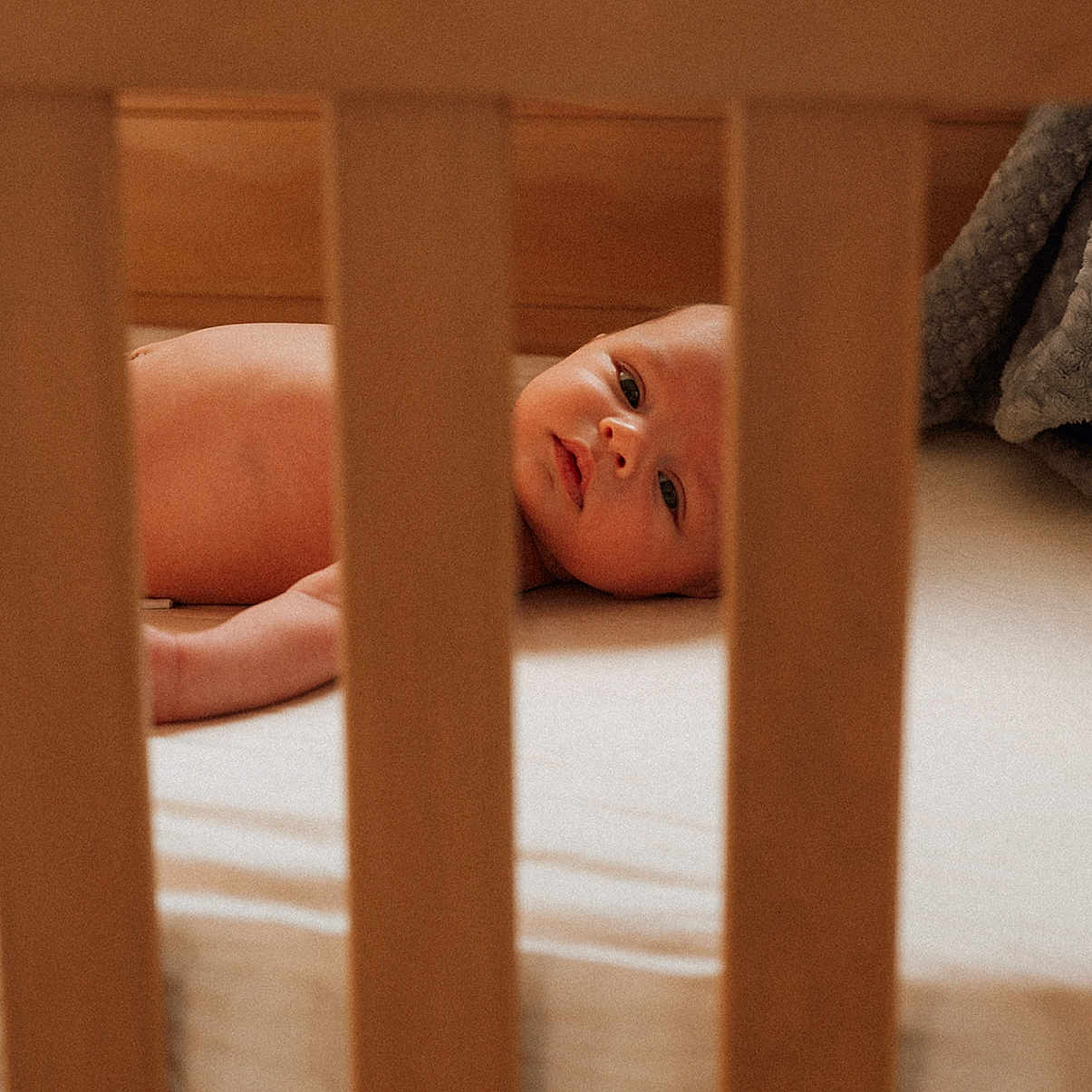 Coast joined the competition — help win amazing prizes! baby, bedding, blanket, candid, closeup, crib, crib_slats, eyes, face, gaze, gray_blanket, infant, lying_down, mattress, newborn, nursery, portrait, soft_light, warm_tones, wooden_crib