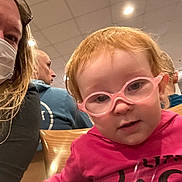 Nora joined the competition — help win amazing prizes! toddler, child, glasses, pink_shirt, smiling_face, curious_expression, woman, mask, man, blue_shirt, wooden_chair, indoor, ceiling_lights, people, portrait, close_up, seated, casual_clothing, hair, face