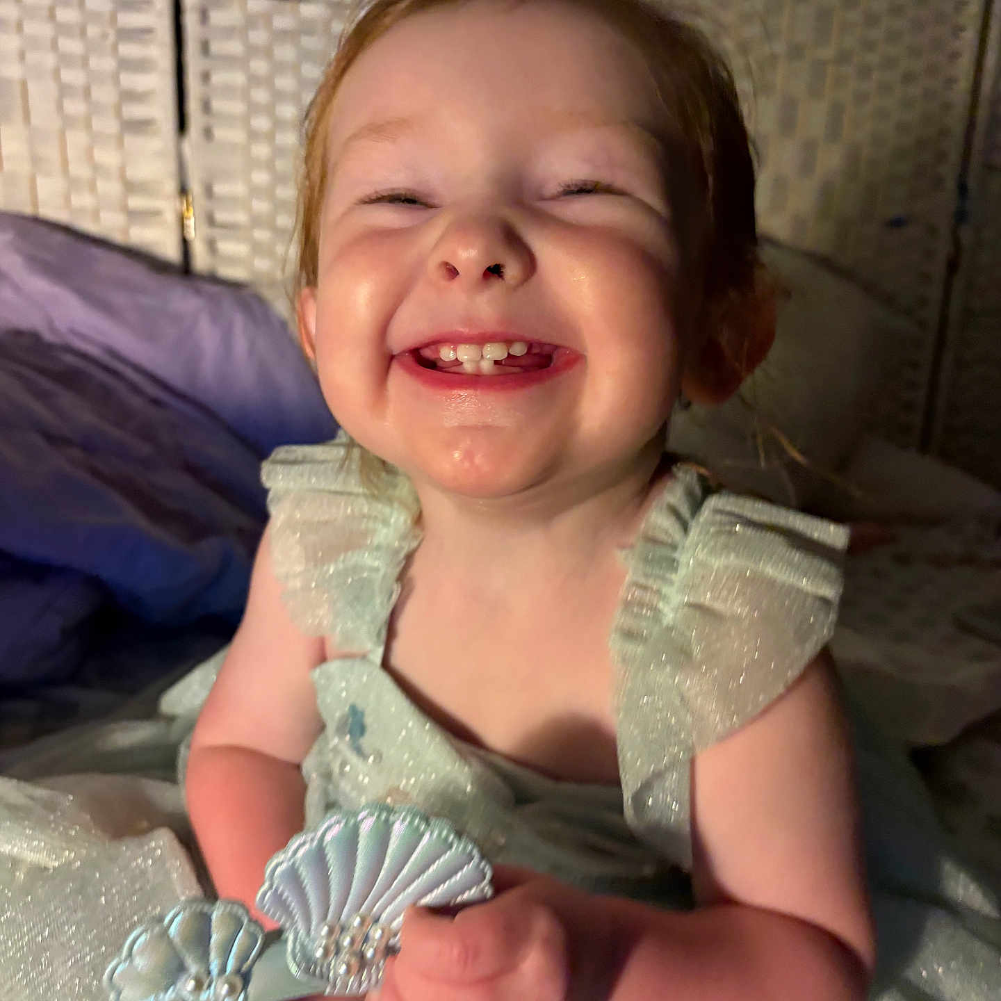 Nora joined the competition — help win amazing prizes! toddler, child, smiling, happy, dress, sparkly, toy, seashell, indoor, portrait, face, hands, cute, young_child, joyful, closeup, person, fabric, woven_background, lighting