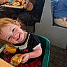 toddler, child, smile, bread, food, high_chair, restaurant, table, people, indoor, red_hair, clothing, black_top, red_skirt, cute, happy, dining, family, person, seat