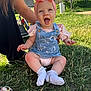baby, child, smiling, happy, outdoor, grass, headband, bow, denim_overalls, socks, person, sunlight, nature, candid, sitting, supporting_hand, greenery, daylight, casual_clothing, infant