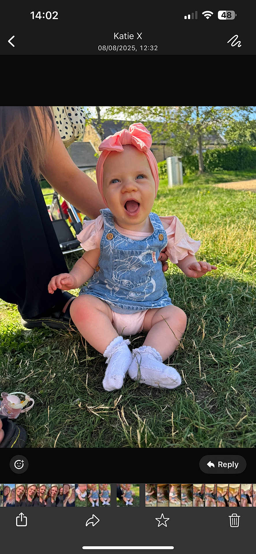Isabella-Rayne is registered to the contest to win money with this photo: baby, child, smiling, happy, outdoor, grass, headband, bow, denim_overalls, socks, person, sunlight, nature, candid, sitting, supporting_hand, greenery, daylight, casual_clothing, infant