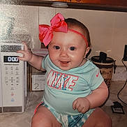 Emerie joined the competition — help win amazing prizes! baby, infant, child, smiling, sitting, kitchen, microwave, pink_bow, headband, nike, clothing, countertop, appliance, cabinet, happy, indoor, person, cute, playful, young