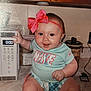 baby, infant, child, smiling, sitting, kitchen, microwave, pink_bow, headband, nike, clothing, countertop, appliance, cabinet, happy, indoor, person, cute, playful, young