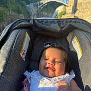 Naylani is registered to the contest to win money with this photo: baby, child, infant, stroller, smiling, sleeping, outdoor, travel, bridge, waterfall, stone_architecture, nature, sunlight, portrait, dress, pacifier, toy, seated, tourist_attraction, family_outing