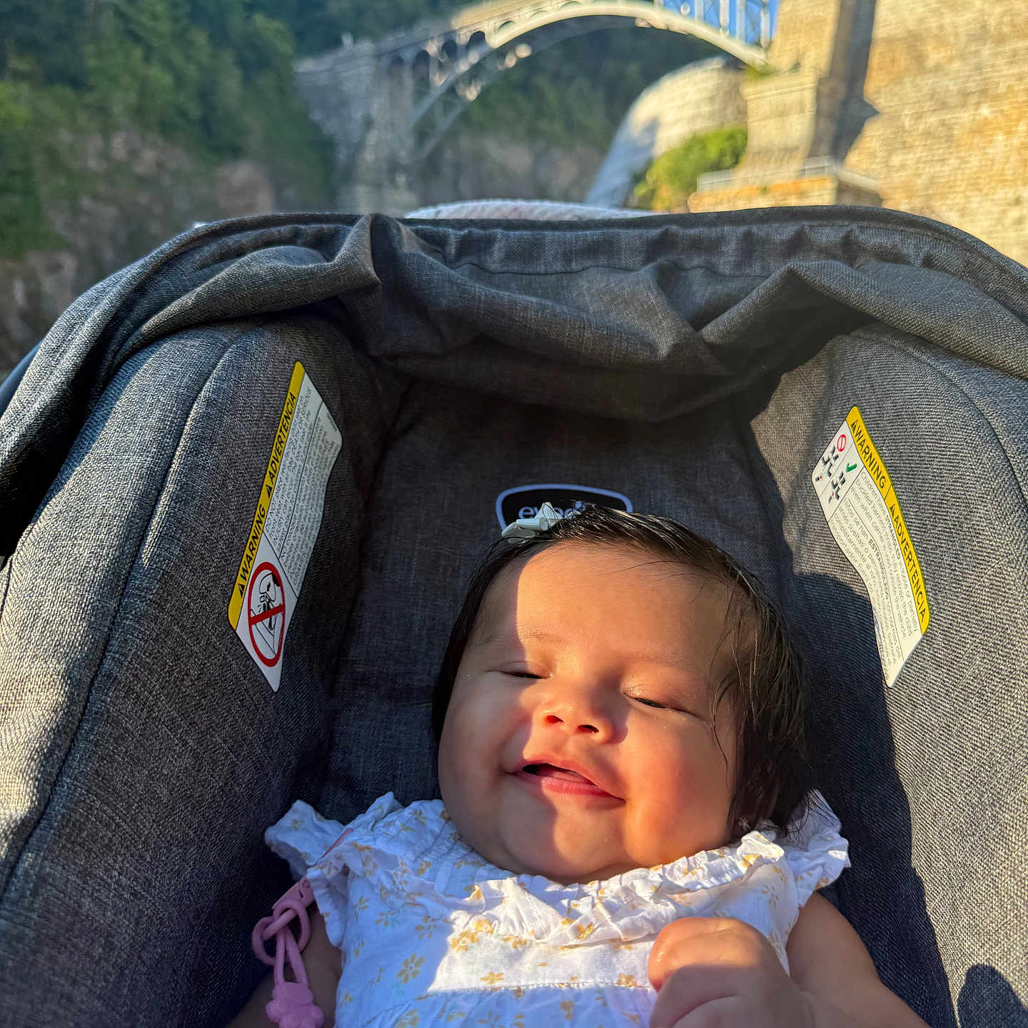 Naylani is registered to the contest to win money with this photo: baby, child, infant, stroller, smiling, sleeping, outdoor, travel, bridge, waterfall, stone_architecture, nature, sunlight, portrait, dress, pacifier, toy, seated, tourist_attraction, family_outing