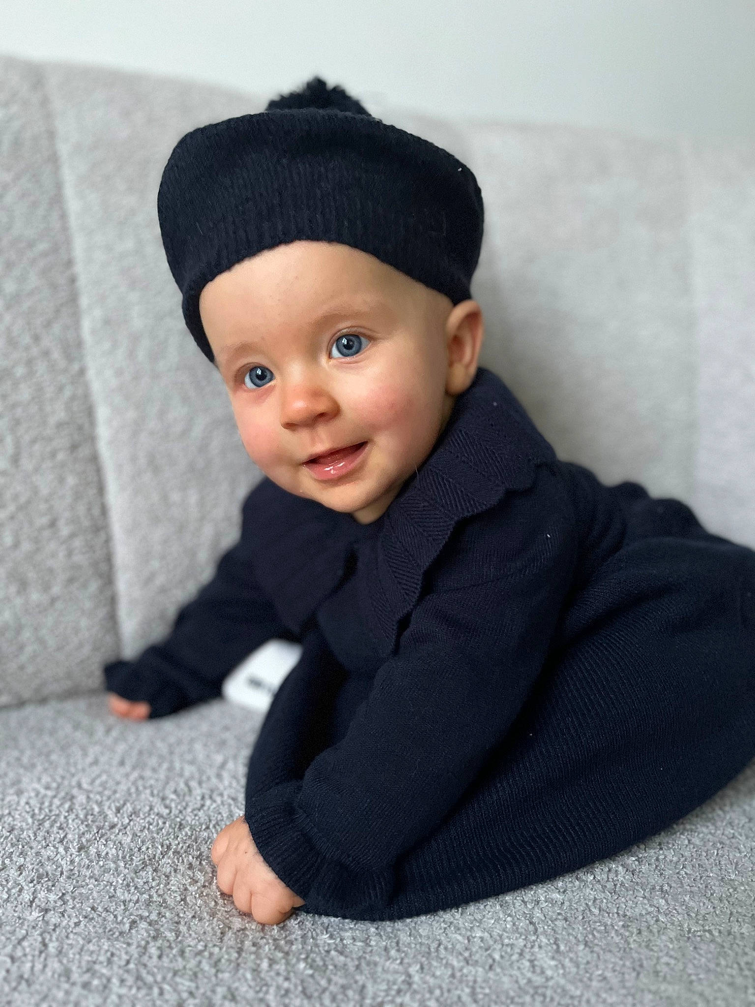 Angèle a rejoint le concours — aidez-le/la à gagner de superbes lots ! baby, baby_toddler_clothing, beanie, cap, child, collar, comfort, face, flooring, fur, hat, headgear, headwear, knit_cap, outerwear, person, sitting, sleeve, smile, toddler