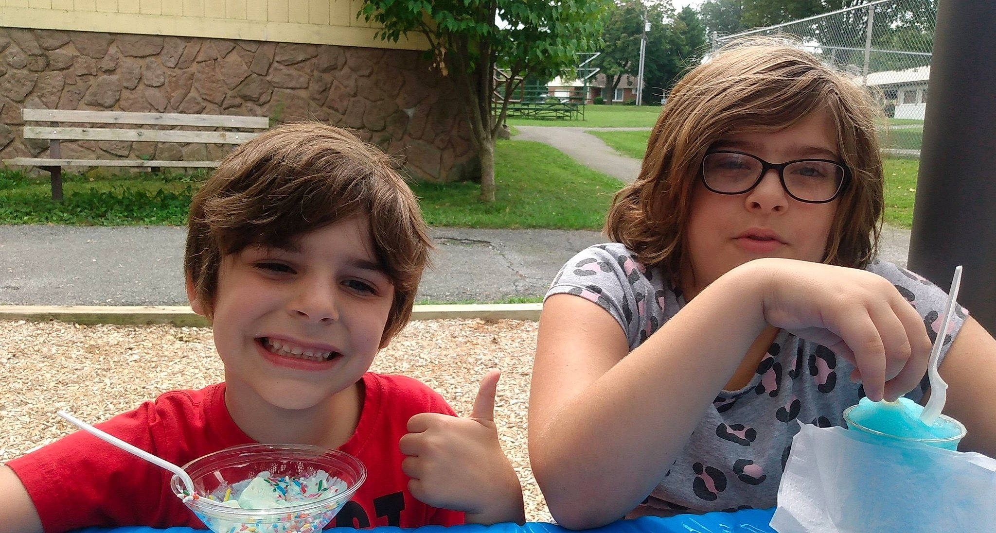 Cole is registered to the contest to win money with this photo: chair, child, eyewear, face, facial_expression, fun, grass, happy, joy, leisure, people, person, plant, recreation, sharing, smile, summer, table, tableware, toddler