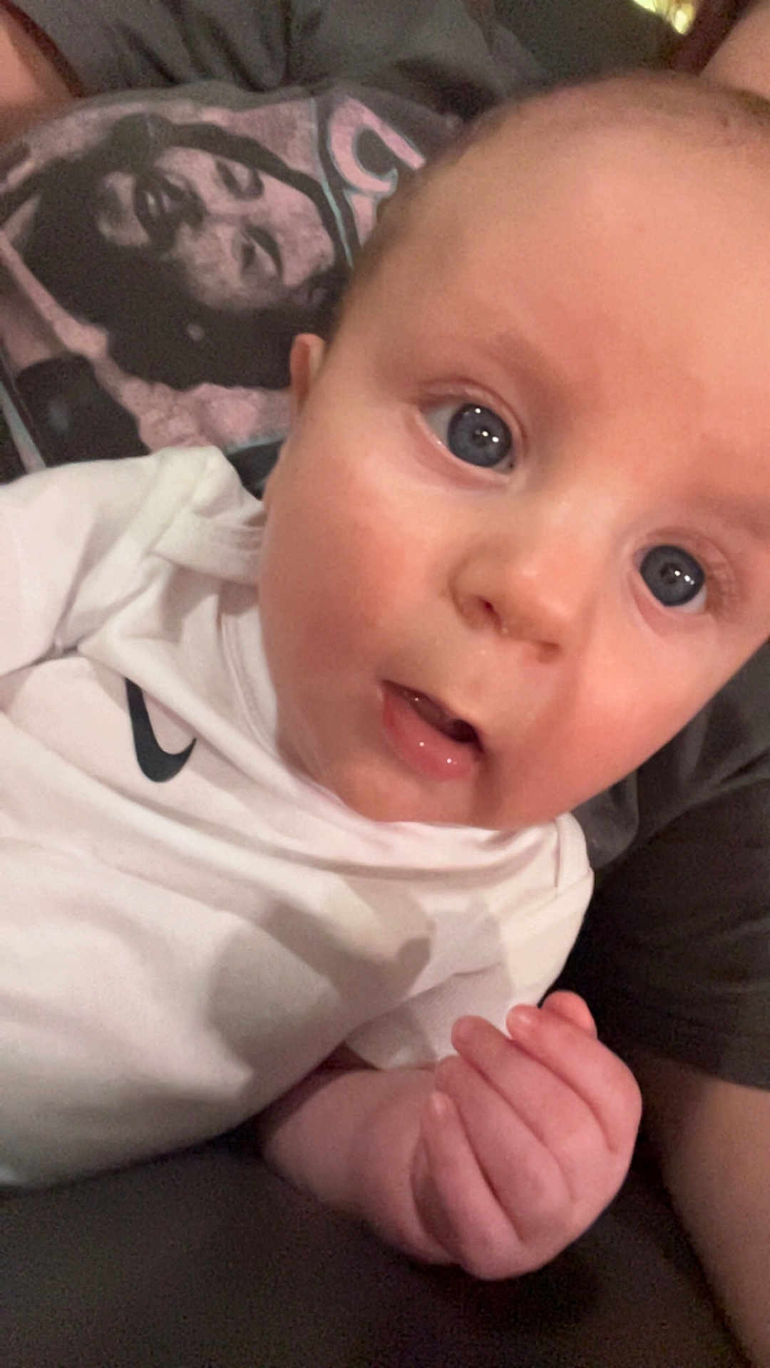 Bentley joined the competition — help win amazing prizes! baby, infant, blue_eyes, white_shirt, nike_logo, hand, face, person, portrait, close_up, curious, indoor, toddler, skin, expression, clothing, human, young_child, sitting, casual