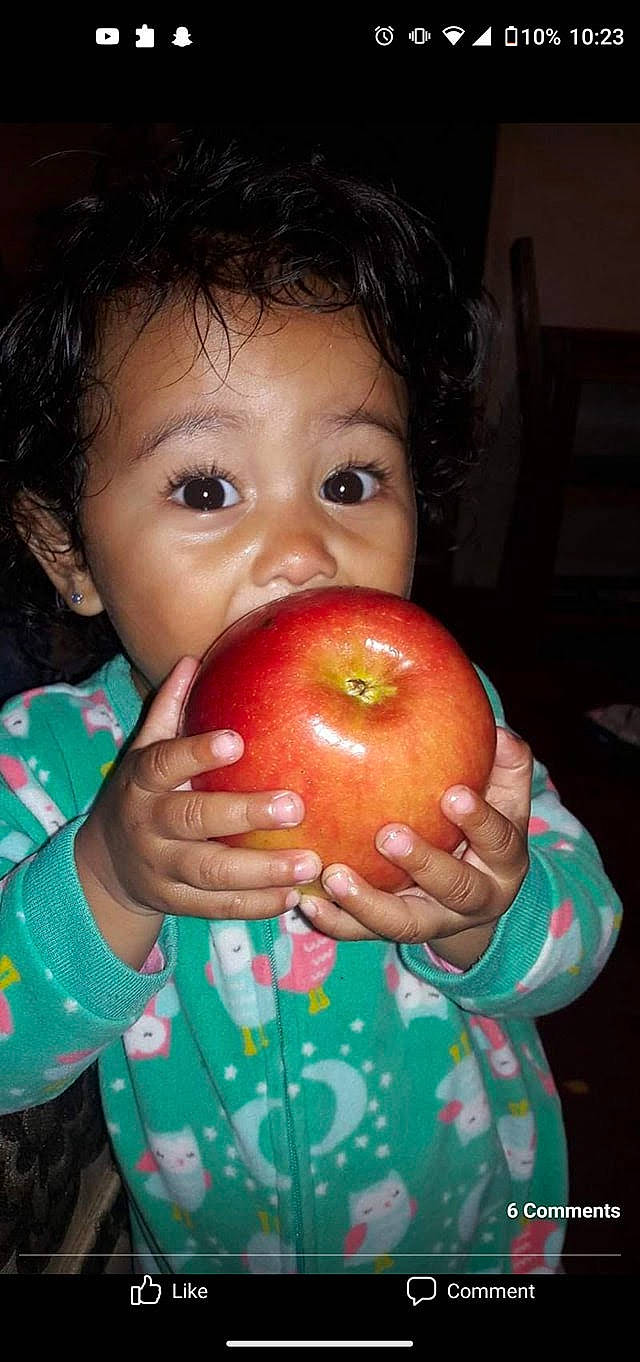 Emely is registered to the contest to win money with this photo: accessory_fruit, apple, child, eye, eyelash, finger, food, fruit, green, hand, lip, local_food, mouth, natural_foods, nose, person, plant, produce, seedless_fruit, skin
