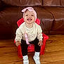 Mckenzie joined the competition — help win amazing prizes! toddler, child, smiling, sitting, red_chair, pink_headband, white_shoes, black_pants, cream_sweater, wooden_floor, leather_couch, indoor, happy, snack, cute, portrait, baby, headwear, footwear, person