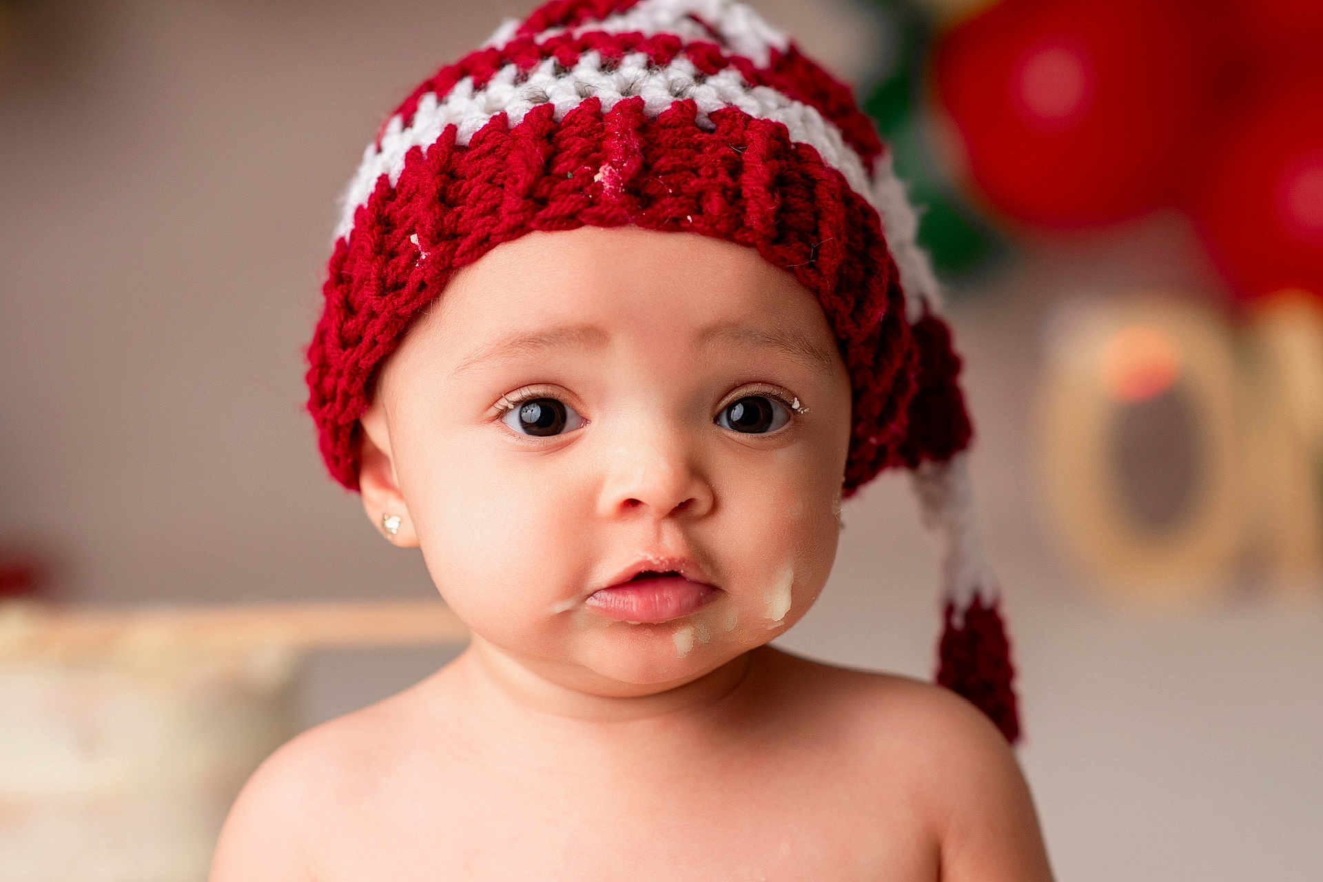 Mckenzie joined the competition — help win amazing prizes! baby, child, face, hat, knitted_hat, red_and_white, food_smear, cute, portrait, indoors, earrings, big_eyes, expression, holiday, festive, soft_light, closeup, skin, adorable, messy