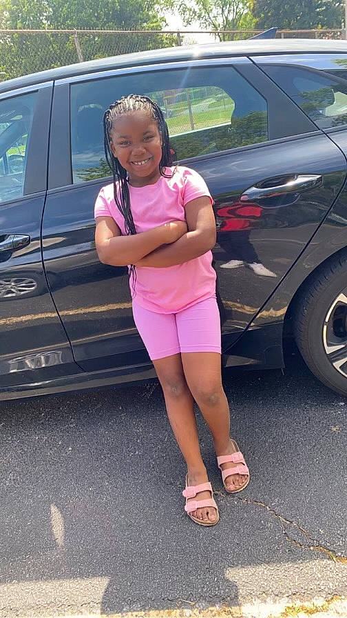 Gracie is registered to the contest to win money with this photo: alloy_wheel, automotive_design, automotive_exterior, automotive_lighting, automotive_tire, bumper, car, dress, footwear, hand, hood, joy, land_vehicle, leg, motor_vehicle, person, shoe, tire, vehicle, vehicle_door