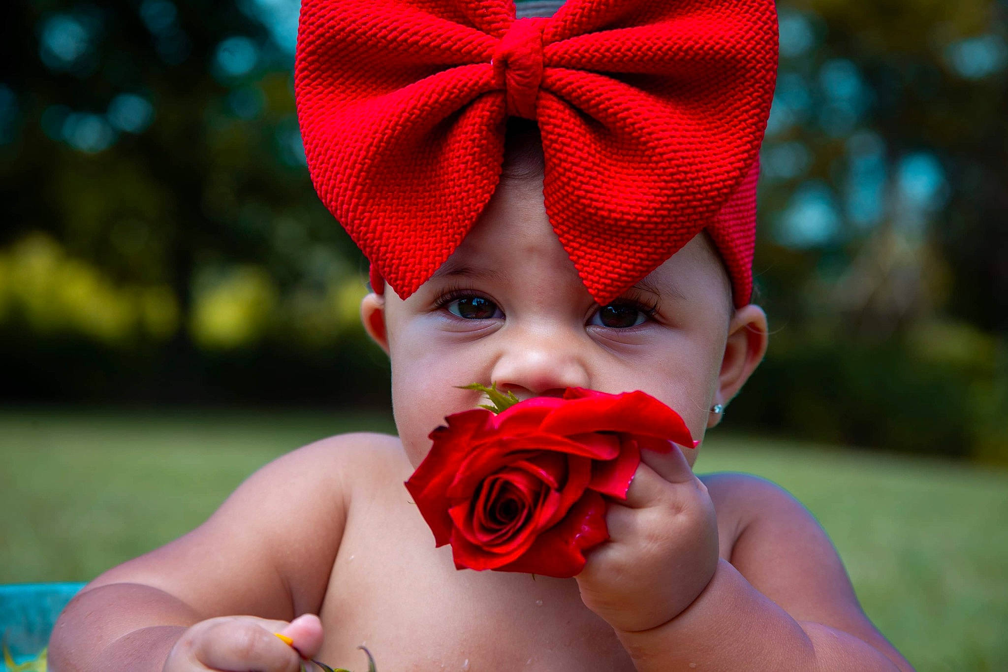 Jupiter is registered to the contest to win money with this photo: baby, cheek, child, close_up, facial_expression, finger, fun, hair_accessory, head, headgear, lip, mouth, nose, person, petal, photography, pink, red, skin, smile