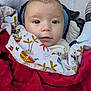 baby, infant, blanket, red_blanket, patterned_blanket, closeup, face, eyes, expression, cozy, padded_seat, clothing, soft_texture, cute, child, portrait, indoors, comfort, young, warm