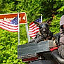 dog, motorcycle, biker_goggles, american_flags, outdoor, greenery, person, riding, helmet, metal_box, leather, travel, road_trip, pet, canine, vehicle, casual, side_view, daylight, adventure