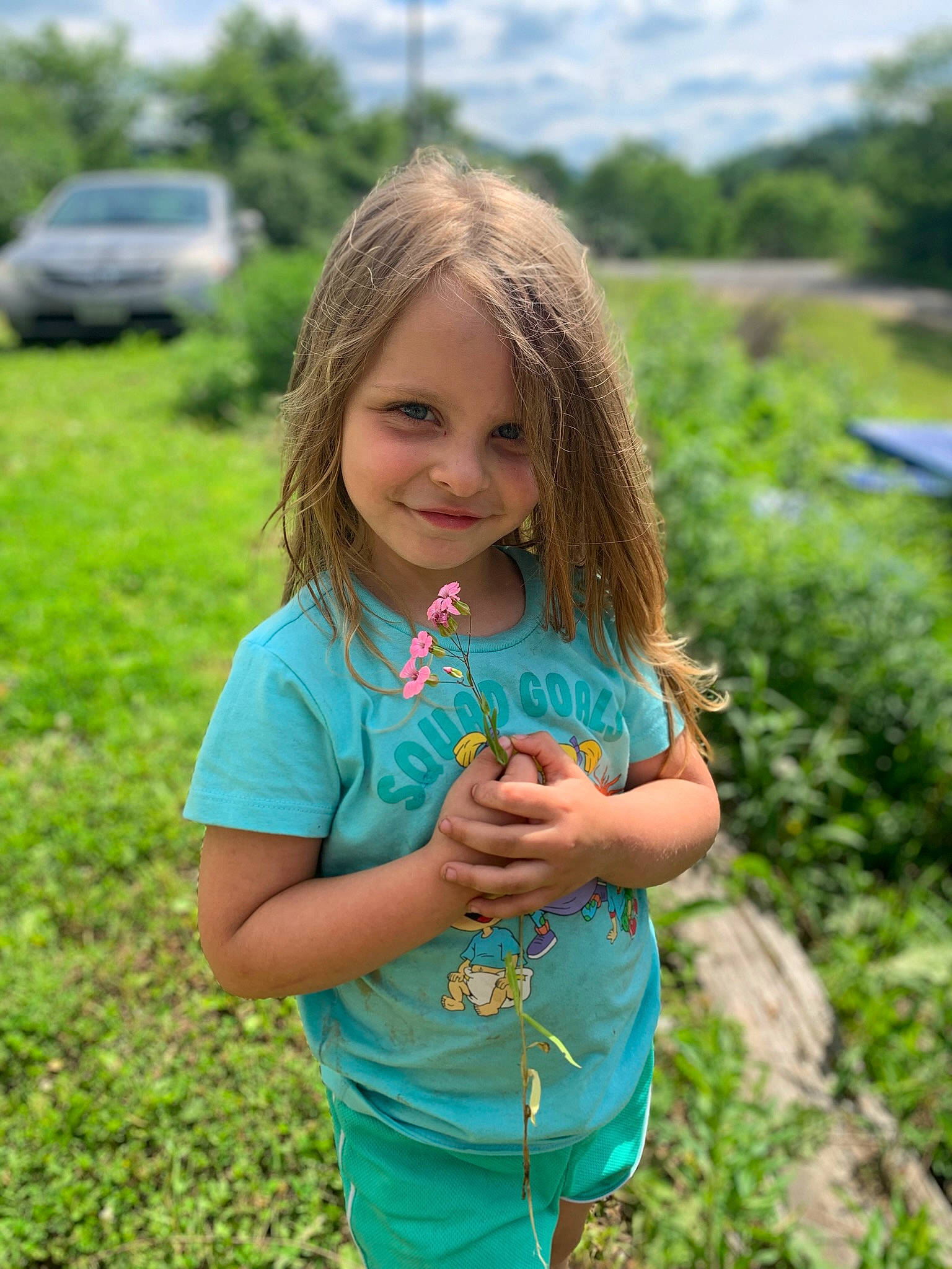 Teagan is registered to the contest to win money with this photo: car, clothing, facial_expression, grass, grass_family, grassland, happy, joy, landscape, leaf, leisure, meadow, natural_environment, nature, people_in_nature, person, plant, rural_area, skin, smile