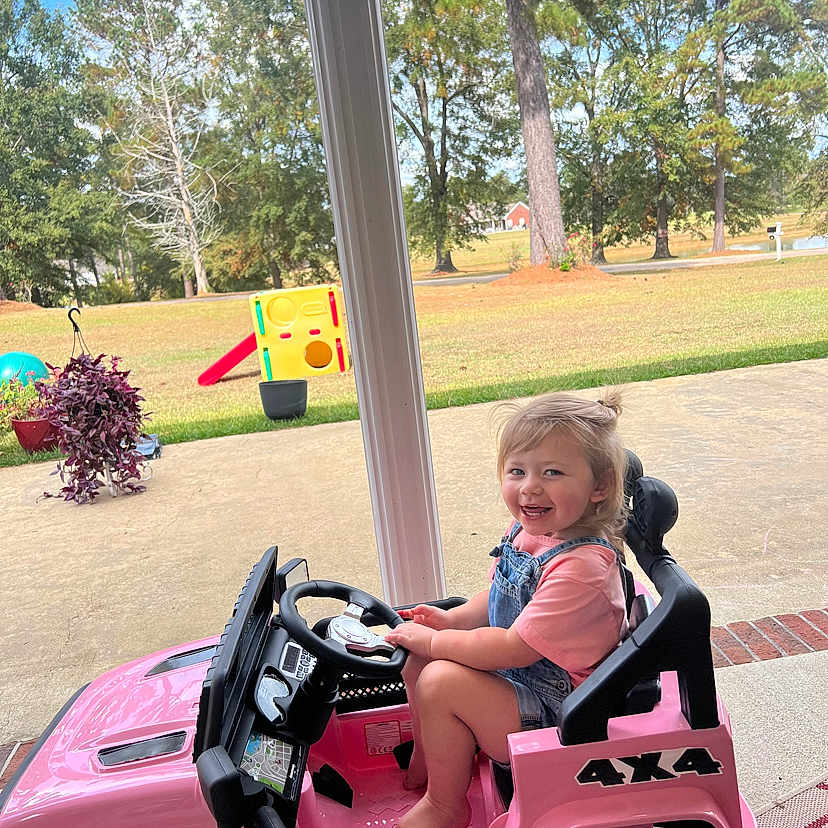 Brynnlee is registered to the contest to win money with this photo: buggy, child, face, female, girl, grass, head, machine, nature, outdoors, park, person, photography, plant, portrait, summer, transportation, tree, vegetation, wheel
