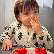 Amélie participe au concours pour gagner de l'argent avec cette photo : toddler, child, strawberry, fruit, plate, table, indoors, window, curtain, onesie, patterned_clothing, eating, hand, face, brown_hair, cute, natural_light, portrait, food, young_child