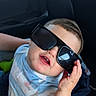 toddler, child, sunglasses, car_seat, smiling, portrait, baby, person, clothing, short_sleeves, cute, funny, hand, seat, car_interior, casual, young_child, fashion, happy, indoor