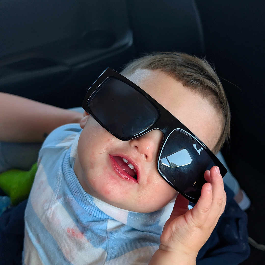 Giovonny is registered to the contest to win money with this photo: toddler, child, sunglasses, car_seat, smiling, portrait, baby, person, clothing, short_sleeves, cute, funny, hand, seat, car_interior, casual, young_child, fashion, happy, indoor