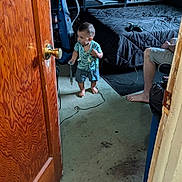Giovonny joined the competition — help win amazing prizes! toddler, child, barefoot, indoors, cord, vacuum_cleaner, bed, person, poster, door, floor, carpet, furniture, sitting, clothing, handheld_object, room, technology, adult, casual