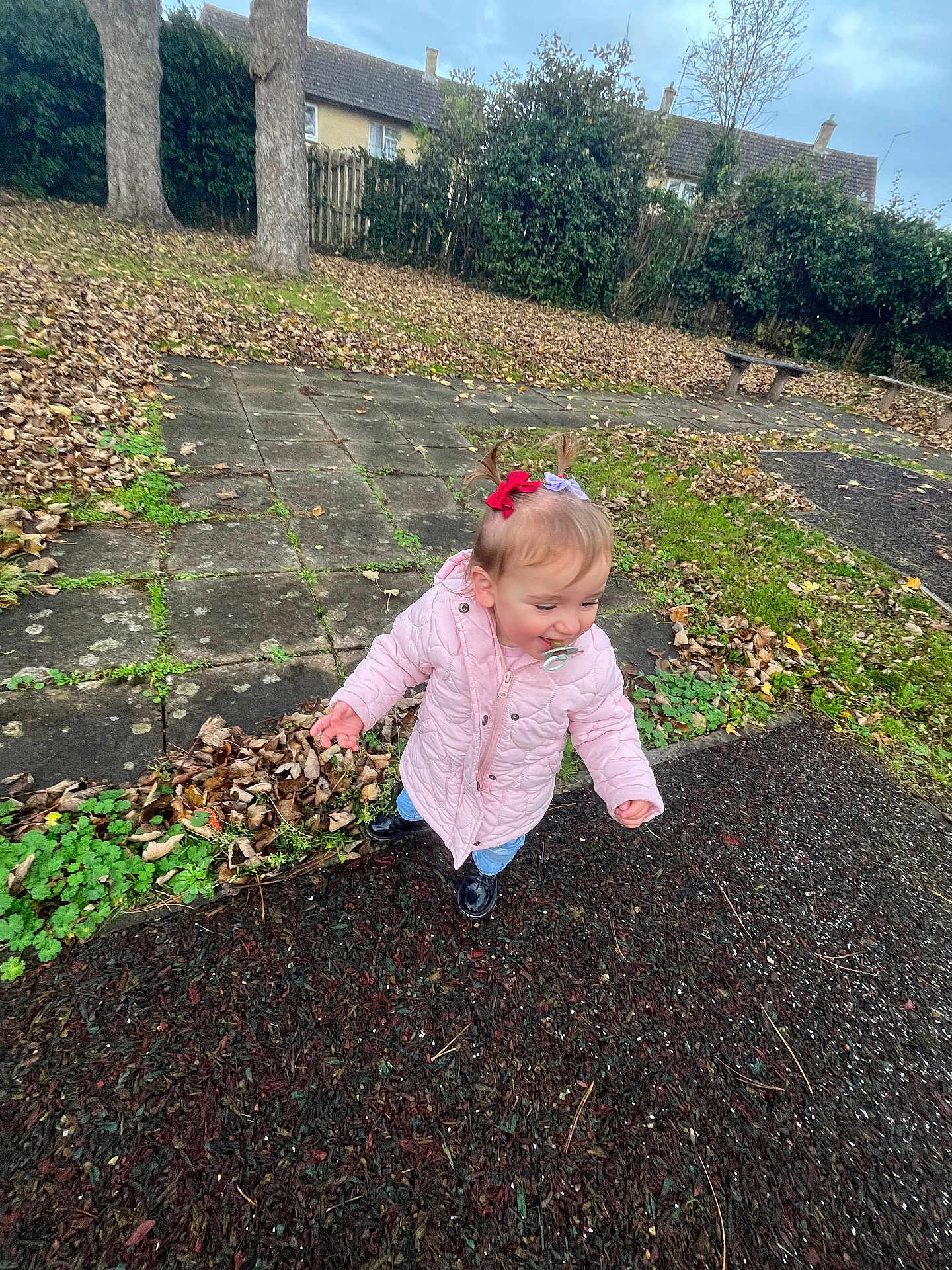 Rayah joined the competition — help win amazing prizes! toddler, child, pink_jacket, pigtails, hair_bows, pacifier, autumn, fallen_leaves, outdoor, park, sidewalk, trees, grass, shoes, curious, playground, bench, overcast_sky, young_child, exploring