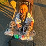 child, toddler, stroller, outdoor, sunlight, smile, leopard_print, leggings, shoes, jacket, pavement, happy, baby, seatbelt, toy, pacifier, playful, daylight, person, wheel