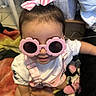 Amari joined the competition — help win amazing prizes! accessory, baby, blanket, bow, child, cute, face, fashion, hair_accessory, happy, indoor, overalls, person, pink, playful, smiling, sunglasses, toddler, toy, white_shirt
