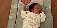 Xavier-James is registered to the contest to win money with this photo: baby, newborn, onesie, infant, lying_down, changing_mat, cloud_pattern, rainbow, wooden_floor, sleepwear, child, cute, small_hand, calm, indoors, soft_toy, blanket, face, person, cozy